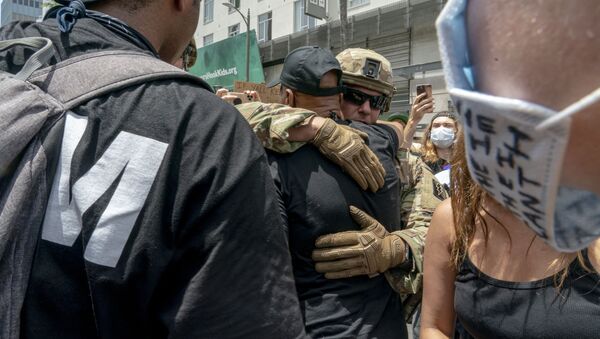 Протестующие и офицеры Национальной гвардии США обнимаются на демонстрации в связи со смертью Джорджа Флойда, Лос-Анджелес - Sputnik Узбекистан