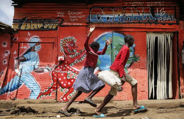Nayrobi, Kibera xarobalarida bolalar koronavirusga bag‘ishlangan graffiti oldidan yugurmoqda (Keniya), 03.06.20. - Sputnik O‘zbekiston