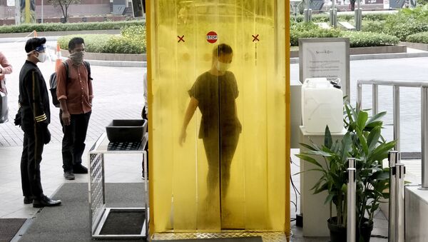 Женщины опрыскивается дезинфицирующим средством внутри камеры в Джакарте - Sputnik Ўзбекистон