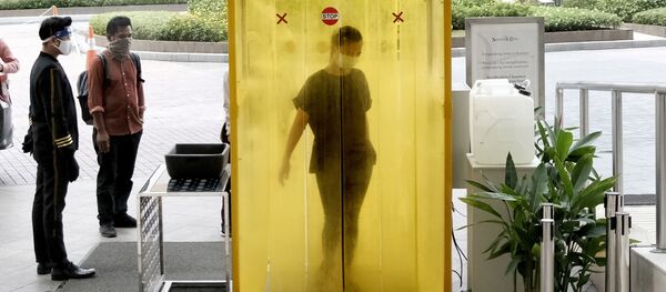 Женщины опрыскивается дезинфицирующим средством внутри камеры в Джакарте Женщины опрыскивается дезинфицирующим средством внутри камеры в Джакарте - Sputnik Ўзбекистон