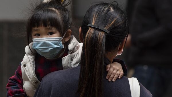 Девочка в защитной маске на руках у матери на одной из улиц в Гонконге - Sputnik Ўзбекистон