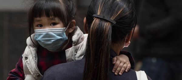 Девочка в защитной маске на руках у матери на одной из улиц в Гонконге - Sputnik Узбекистан