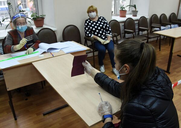 Член избирательной комиссии регистрирует участницу голосования по внесению поправок в Конституцию РФ на избирательном участке №727 во Владивостоке - Sputnik Узбекистан