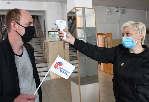 Измерение температуры участника голосования по внесению поправок в Конституцию РФ на избирательном участке №209 в Чите - Sputnik Узбекистан