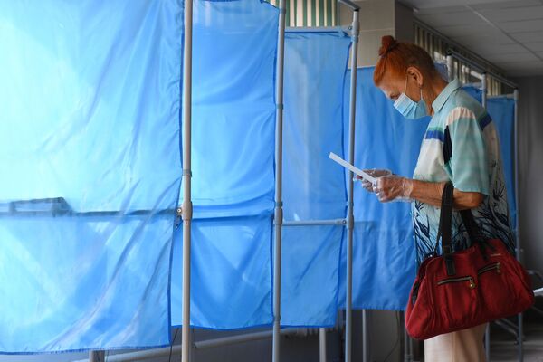 Женщина принимает участие в голосовании по внесению поправок в Конституцию РФ на избирательном участке №1503 в Новосибирске - Sputnik Узбекистан