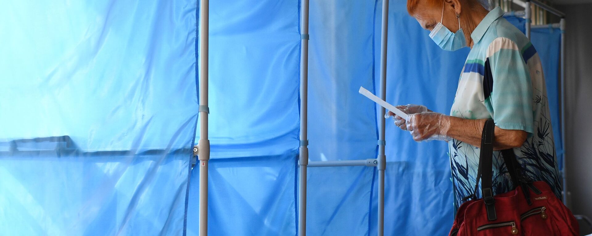 Женщина принимает участие в голосовании по внесению поправок в Конституцию РФ на избирательном участке №1503 в Новосибирске - Sputnik Узбекистан, 1920, 20.09.2021