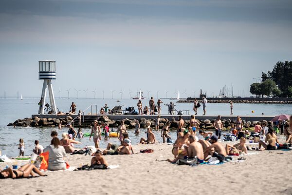 Люди наслаждаются жаркой погодой на пляже Бельвю к северу от Копенгагена, Дания - Sputnik Узбекистан