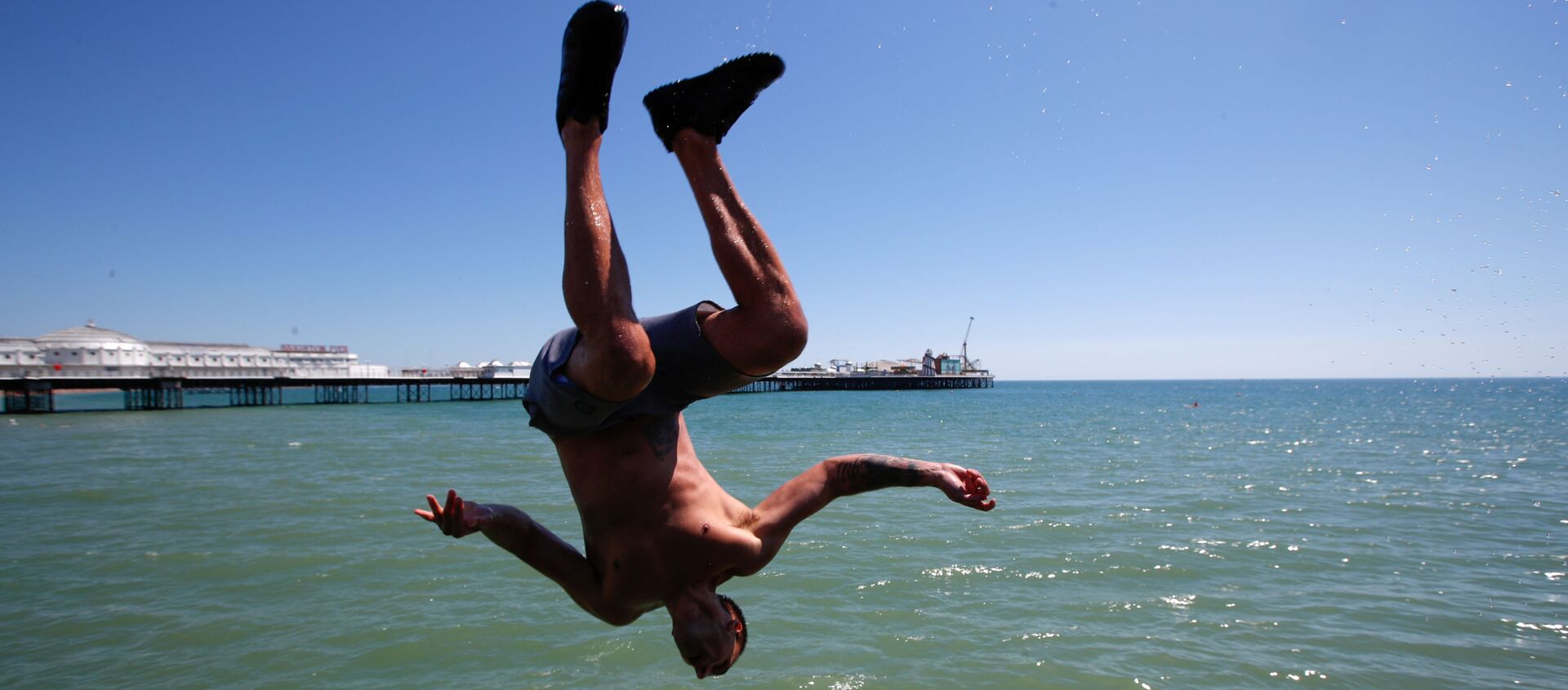Мужчина прыгает в воду на пляже в Брайтоне, Великобритания - Sputnik Ўзбекистон, 1920, 15.08.2020