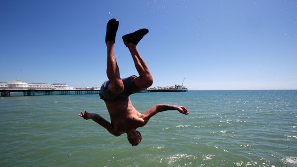 Мужчина прыгает в воду на пляже в Брайтоне, Великобритания - Sputnik Ўзбекистон