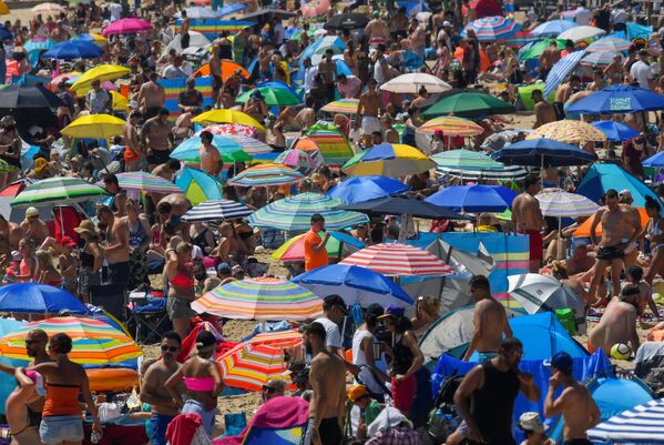 Люди наслаждаются жаркой погодой на пляже в Борнмуте, Великобритания - Sputnik Узбекистан