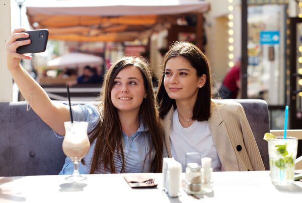 Девушки в летнем кафе на улице Старый Арбат после снятия карантина в Москве - Sputnik Узбекистан