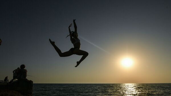 Девушка во время прыжка с пирса на пляже в посёлке городского типа Новофёдоровка Сакского района - Sputnik Узбекистан