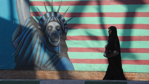 Женщина идет вдоль стены здания бывшего посольства США в Тегеране - Sputnik Ўзбекистон