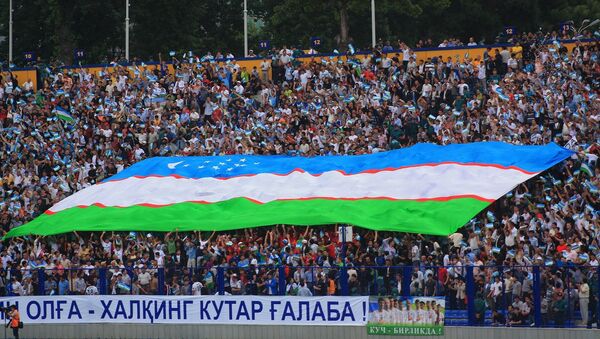 Футбольные болельщики на трибуне держат флаг Узбекистана - Sputnik Ўзбекистон