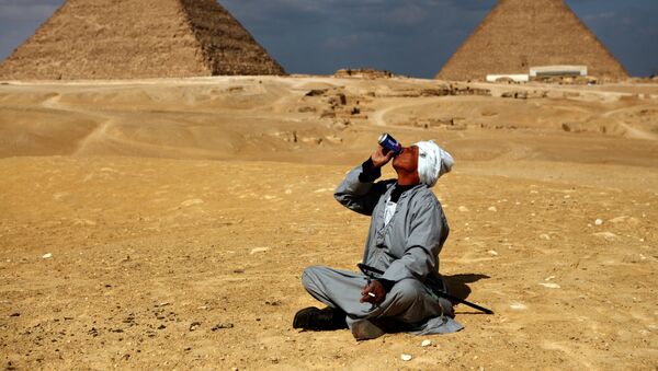 Мужчина пьет газированный напиток у пирамид в Гизе - Sputnik Узбекистан