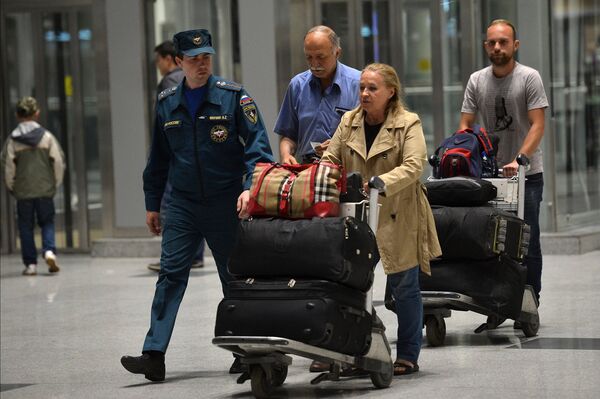 Сотрудник МЧС помогает донести багаж пассажирам Сотрудник МЧС помогает донести багаж пассажирам - Sputnik Узбекистан