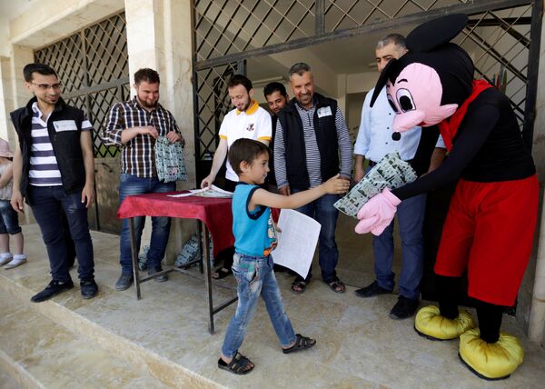 A man dressed up as Mickey Mouse distributes certificates and gifts to students during a celebration marking the end of the school year, at 'Syria, The Hope' school on the outskirts of the rebel-controlled area of Maaret al-Numan town, in Idlib province, Syria June 1, 2016 - Sputnik O‘zbekiston