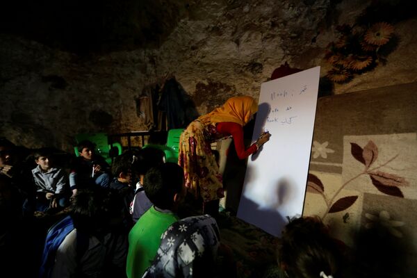 Учитель проводит урок для детей в пещере в деревне Трамла в провинции Идлиб - Sputnik Узбекистан