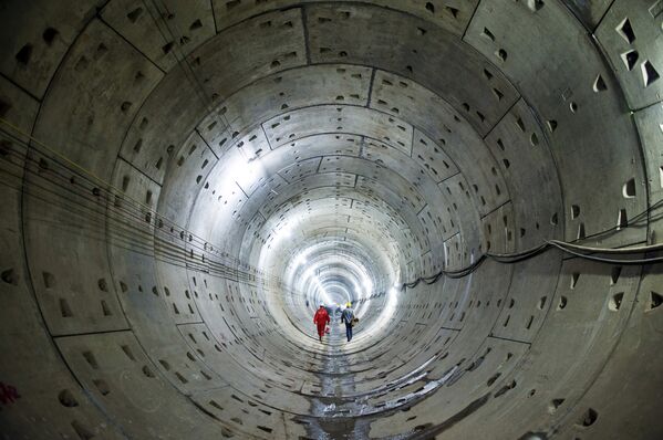 Рабочие идут вдоль тоннеля на строительной площадке метро - Sputnik Узбекистан