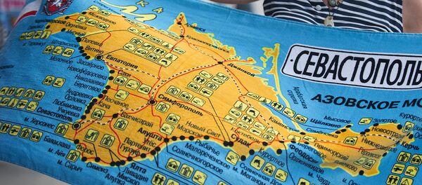 Женщина рассматривает пляжное полотенце с картой Крыма Женщина рассматривает пляжное полотенце с картой Крыма - Sputnik Узбекистан