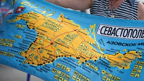 Женщина рассматривает пляжное полотенце с картой Крыма - Sputnik Узбекистан