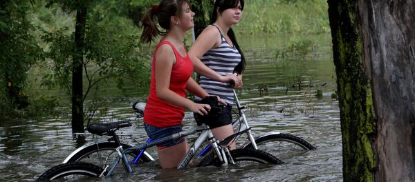 Девушки с велосипедами на затопленной улице Девушки с велосипедами на затопленной улице - Sputnik Ўзбекистон