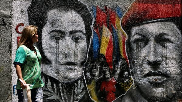 Женщина смотрит на граффити, изображающей  национального героя Венесуэлы Симона Боливара и бывшего президента Венесуэлы Уго Чавеса в центре Каракаса - Sputnik Узбекистан