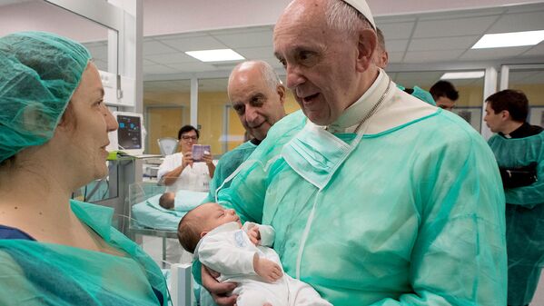Глава Римской католической церкви  Франциск держит новорожденную ребенка, во время посещения  больницы Сан-Джованни в Риме - Sputnik Узбекистан
