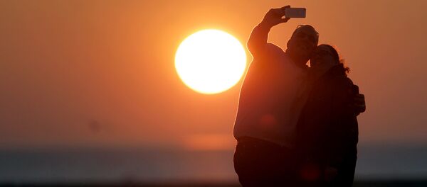Молодые люди делают селфи на фоне заката - Sputnik Узбекистан