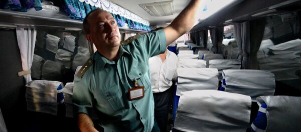 Сотрудник таможни осматривает автобус - Sputnik Узбекистан