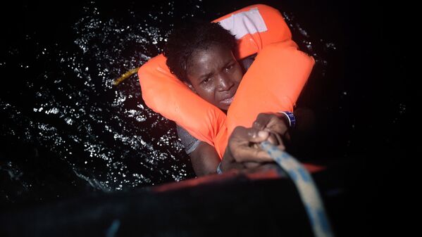 Мигрант держится за веревку во время спасательной операции в Средиземном море вблизи Ливии - Sputnik Узбекистан
