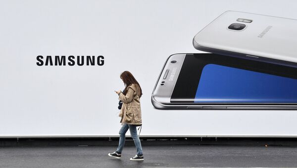 Женщина проходит мимо стенда с изображением телефона Samsung - Sputnik Узбекистан