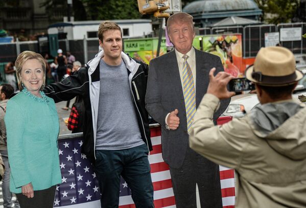 Мужчина фотографируется с ростовыми фигурами кандидатов в президенты США в Нью-Йорке. - Sputnik Узбекистан
