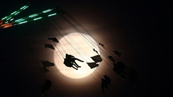 Люди на аттракционе в Лондоне фотографировались на фоне полной Луны накануне суперлуния - Sputnik Узбекистан