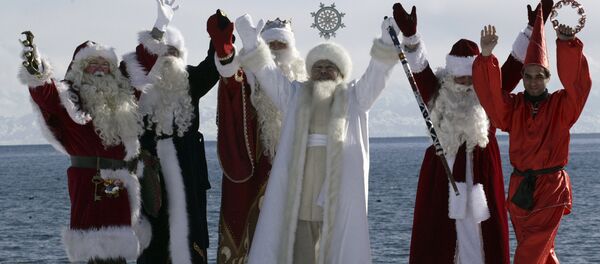 Актеры в костюмах шести Дедов Морозов со всего мира, включая (слева направо) Санта Клауса, Аяз_Ата из Казахстана, из Кыргызстана, российского Деда Мороза, иранского Хаджи Фируз, позируют на фоне озера Иссык-Куль - Sputnik Узбекистан