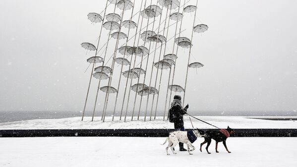 Женщина прогуливается про набережной во время сильного снегопада в Греции - Sputnik Узбекистан