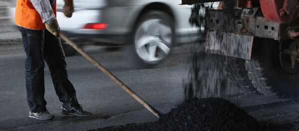 Работник дорожного хозяйства укладывает новый асфальт - Sputnik Узбекистан