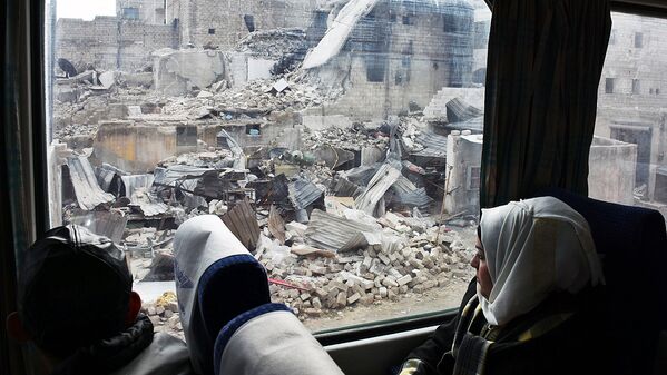 Сирийская женщина смотрит из окна поезда на разрушенные здания в Восточном Алеппо - Sputnik Узбекистан