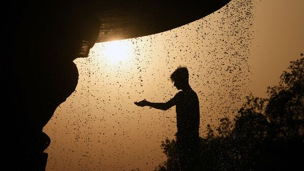 An Indian man cools himself under a fountain near India Gate in New Delhi - Sputnik Узбекистан