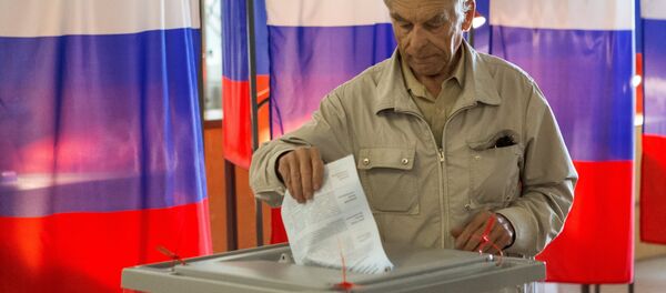 Избиратель опускает бюллетень в урну Избиратель опускает бюллетень в урну - Sputnik Узбекистан