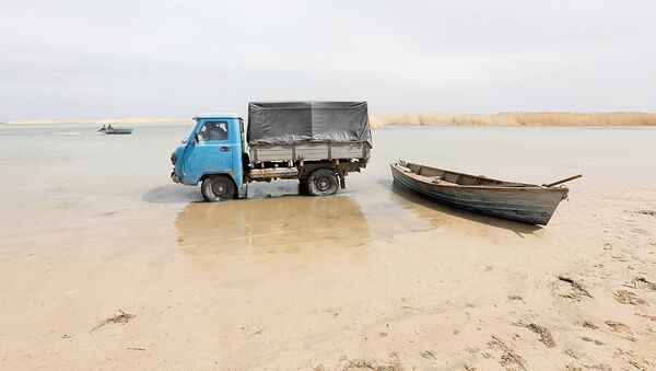 Fishermen ride in a truck to collect fish from a boat in shallow water by the Aral Sea, outside the village of Karateren, south-western Kazakhstan, April 15, 2017. Akespe, home to some 250 people, and Karateren, inhabited by about 150, used to be dominated by fishermen until the water receded too far away - but it is now back in Karateren - Sputnik Узбекистан