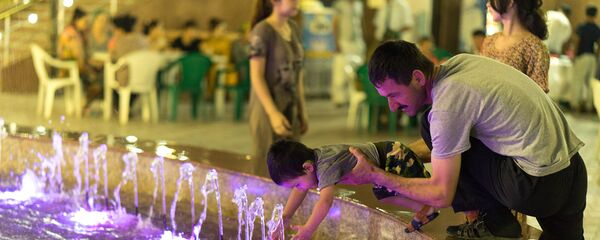 Мужчина играет у фонтана с ребенком Мужчина играет у фонтана с ребенком - Sputnik Узбекистан