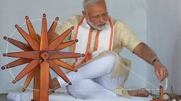 Премьер-министр Индии Нарендра Моди вращает хлопок на колесе во время визита в Ахмадабаде - Sputnik Узбекистан