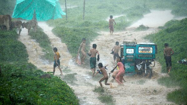 Дети играют под дождем в эвакуационном центре в то время, как войска продолжают наступление против боевиков Мауте в Марави (Филиппины) - Sputnik Узбекистан