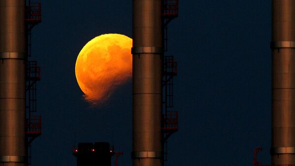Восходящая луна во время частичного лунного затмения за трубами электростанции в Делимаре, недалеко от Мальты - Sputnik Узбекистан