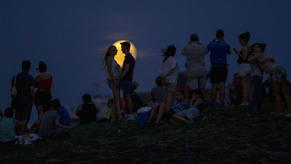 Люди наблюдают за восходящей луной во время частичного лунного затмения на вершине холма в парке Тио Пио в Мадриде - Sputnik Узбекистан