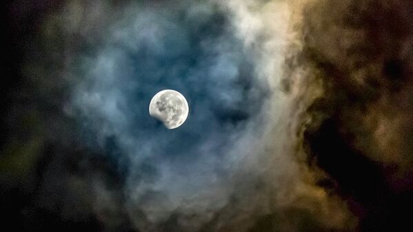 Луна, обрамленная пеплом от вулкана Маунт Синабунг, видна во время частичного лунного затмения в провинции Северная Суматра в Индонезии - Sputnik Узбекистан
