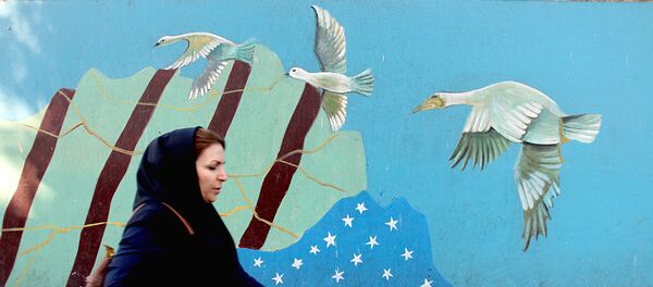 Женщина проходит мимо граффити с изображением флага США в Тегеране - Sputnik Узбекистан