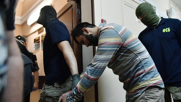 Сотрудники правоохранительных органов выводят одного из подозреваемых в подготовке взрывов в Москве - Sputnik Узбекистан