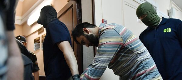 Сотрудники правоохранительных органов выводят одного из подозреваемых в подготовке взрывов в Москве - Sputnik Узбекистан